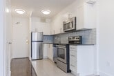 Located in the heart of Toronto's Church-Wellesley Village, this one-bedroom, one-bathroom unit offers a practical and well-appointed layout across a single floor. Rich parquet hardwood flooring flows throughout the living room and bedroom, lending warmth and character to the bright, white-walled interior.

The living area is anchored by floor-to-ceiling sliding glass doors that open onto a private balcony, framing views of the surrounding Toronto cityscape. Large windows allow natural light to fill the space throughout the day.

The kitchen is efficiently designed with a full suite of stainless steel appliances — including a refrigerator, electric range, built-in microwave, and dishwasher — complemented by white shaker-style cabinetry, dark countertops, and a light blue subway tile backsplash. Tile flooring carries through the kitchen area for easy maintenance.

The bedroom is a comfortable, well-proportioned retreat with the same warm parquet flooring and access to the hallway. The four-piece bathroom features a full soaker tub and shower combination, finished with neutral horizontal stone-look tiles for a clean, contemporary feel.

Two hallways provide practical circulation throughout the unit. The overall aesthetic is clean and modern, making this a well-suited urban residence in one of Toronto's most vibrant and walkable neighbourhoods.