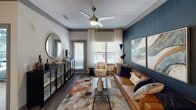 Located at 11702 S Old Statesville Rd in Huntersville, NC, this thoughtfully designed single-floor residence showcases a curated blend of contemporary style and functional living. The open living area makes a strong visual statement with a deep navy textured accent wall, dark hardwood-style flooring, ceiling fan, and abundant natural light streaming through multiple windows dressed with sheer curtains and blinds. The kitchen is well-appointed with two-tone cabinetry—white upper and dark lower cabinets—granite countertops, stainless steel appliances including a side-by-side refrigerator, built-in microwave, and range, plus a dedicated wine rack for added character. Each bedroom is distinctively designed: one features a bold geometric dark-patterned accent wall with carpet flooring and ceiling fan; another showcases a warm golden textured wall with plush carpeting; and a third offers a clean, neutral palette with carpet and ample natural light. Bathrooms include a tiled walk-in shower and a separate soaking tub with stylish patterned curtains. A walk-in closet connects directly to one of the bathrooms, offering excellent storage. Crown molding and ceiling fans are present throughout, contributing to a polished, cohesive aesthetic across the entire residence.