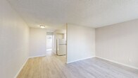 Located in El Paso, TX 79912, this one-bedroom, one-bathroom unit is designed with a functional and straightforward single-floor layout. The living area features light wood-style laminate flooring and neutral beige walls, creating a clean and open atmosphere. A textured ceiling runs throughout the main living spaces, adding a classic residential character. The kitchen is positioned adjacent to the living room and is equipped with a full-size refrigerator, making efficient use of the available space.

The bedroom offers a comfortable footprint, finished with plush carpeting and a wall-mounted air conditioning unit that provides dedicated climate control. A large window dressed with vertical blinds allows natural light to fill the room throughout the day. Storage is well-addressed with a double sliding-door closet that spans a generous portion of one wall, providing ample hanging and shelving space.

The bathroom features a full tub and shower combination finished with clean white subway tiles, complemented by a toilet and wood-style flooring, maintaining a consistent and tidy aesthetic throughout. The overall design of this unit prioritizes practicality and ease of living, with neutral tones and durable finishes that create a bright, welcoming environment suitable for everyday comfort.