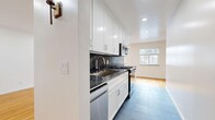 This single-floor, 3-bedroom, 1-bathroom home offers a thoughtfully designed layout across a comfortable footprint. The open kitchen and living area form the heart of the space, where the kitchen stands out with white shaker-style cabinetry, dark marble-look countertops, a matching backsplash, stainless steel appliances — including a gas range, built-in microwave, dishwasher, and French door refrigerator — and slate tile flooring. The kitchen flows into a spacious living area bathed in natural light from multiple windows, showcasing warm-toned hardwood floors that extend throughout the rest of the home. Recessed lighting throughout adds a clean, modern touch. The three bedrooms are well-proportioned, each featuring the same rich hardwood flooring and windows with blinds that allow for controlled natural light. The primary bedroom offers a generous layout with ample room. The full bathroom includes a tub-shower combination with white tile surround, a wood-toned vanity with a dark countertop, slate tile flooring, a frosted privacy window, and a stacked in-unit washer and dryer. Two closets and a hallway complete the layout, providing practical storage throughout this efficiently organized home.