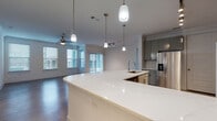 Located at 764 Westinghouse Rd in Georgetown, TX, this single-story residence offers a well-designed, open-concept layout with contemporary finishes throughout. The kitchen serves as the centerpiece of the home, showcasing a large curved white quartz island with an integrated sink, gray flat-front cabinetry, marble-look tile backsplash, stainless steel appliances including a refrigerator with ice maker, electric range, and built-in microwave, all illuminated by pendant lighting and a track lighting system overhead. The kitchen flows seamlessly into the spacious living and dining areas, which feature durable wood-look flooring, ceiling fans, and abundant natural light from multiple windows. A glass door in the living area opens to an outdoor space, enhancing the connection to the exterior. The bedrooms offer walk-in closets with built-in shelving and hanging rods, providing generous storage. The bathroom is clean and functional, featuring a full tub-shower combo with white tile surround, a single vanity with gray cabinetry, and light tile flooring. Arched doorways add an elegant architectural detail, while the consistent neutral color palette and modern hardware create a cohesive, move-in-ready aesthetic throughout the home.