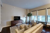 Located at 2303 Mid Ln in Houston's desirable 77027 corridor, this one-bedroom, one-bathroom residence offers a thoughtfully designed single-floor layout. The combined living and dining area serves as the heart of the home, featuring rich dark hardwood flooring, warm neutral walls, and large windows fitted with roller shades that invite abundant natural light while maintaining privacy. The living space is anchored by a distinctive wood media console and complemented by a plush area rug, creating a comfortable and stylish atmosphere. A standout architectural feature is the built-in shelving unit flanking a pass-through opening, which connects the living area to the rest of the unit and provides both display space and functional storage. The kitchen is efficiently designed to maximize utility within its footprint. The bedroom offers a serene retreat with soft carpeting, a ceiling fan, and a closet, while the en-suite bathroom impresses with dark espresso cabinetry, granite countertops, large-format tile flooring, a framed mirror, and a glass-enclosed shower. A dedicated laundry area and two closets further enhance the practical storage throughout. The overall design balances modern finishes with warm, inviting tones, creating a cohesive and comfortable living environment.