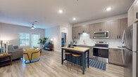 Located at 464 S Kirkman Rd in Orlando, Florida, this well-designed single-floor residence offers a thoughtfully planned layout with modern finishes and a bright, welcoming atmosphere throughout. The open-concept kitchen flows seamlessly into the living area, creating an ideal space for both everyday living and entertaining. The kitchen is outfitted with stainless steel appliances, including a refrigerator, electric range, and over-the-range microwave, complemented by two-tone wood-finish cabinetry, a subway tile backsplash, and a freestanding island with a butcher block top and barstool seating. Light wood-style flooring runs throughout the main living areas, enhancing the airy feel of the space. The living room is generously sized, featuring a ceiling fan, recessed lighting, and a large window that invites natural light. Two well-proportioned bedrooms are finished with plush carpeting and ceiling fans; one bedroom offers a window with natural light and ample room for furnishings. The bathroom features a large vanity with quartz countertop, wood-finish cabinetry, an oversized mirror, and a walk-in shower, with direct access to a spacious walk-in closet equipped with wire shelving. A dedicated entryway with wall-mounted storage adds everyday practicality to this move-in ready home.