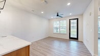 This well-appointed single-floor residence offers two bedrooms and an open-concept layout that maximizes its footprint with a clean, modern aesthetic. Light wood-look flooring runs throughout, complementing the crisp white walls and creating a cohesive, airy feel.

The kitchen is a standout feature, showcasing a two-tone cabinetry design that pairs white upper cabinets with warm wood-toned lower cabinets and a matching kitchen island. Quartz countertops with a marble-like finish, stainless steel appliances, and stylish geometric pendant lights complete the space, giving it a contemporary and functional character.

The open living area flows naturally from the kitchen and is fitted with recessed lighting and a ceiling fan. Large windows dressed with white blinds invite abundant natural light, while a sleek black-framed glass door provides outdoor access and views of the surrounding greenery.

Both bedrooms are bright and comfortable, each featuring light wood-look flooring, ceiling fans, and windows that overlook outdoor surroundings. The primary bedroom includes a well-organized walk-in closet with built-in shelving and double hanging rods, offering generous storage capacity.

A secondary bedroom provides a quiet, versatile space with its own large window. Throughout the residence, clean lines, neutral tones, and quality finishes contribute to a polished and move-in-ready environment.