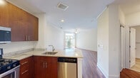 Located at 45 Meadowlands Pkwy in Secaucus, NJ, this efficiently designed single-floor unit offers a thoughtful layout across a combined kitchen and living area, plus one full bathroom. Rich hardwood flooring runs throughout the main living space, complemented by crisp white walls, crown molding, and a ceiling fan that enhances both style and comfort. A sliding glass door opens to a private balcony, allowing natural light to fill the room while providing pleasant outdoor views of the surrounding greenery. The kitchen is well-appointed with warm-toned wood cabinetry extending to the ceiling for generous storage, light granite countertops, and a full suite of stainless steel appliances including a gas range, built-in microwave, and refrigerator. The layout maximizes every inch of counter and cabinet space, making the kitchen highly functional. The bathroom features tile flooring, a dark granite vanity countertop atop wood cabinetry, a large mirror, and a tiled shower, offering a clean and modern aesthetic. Throughout the unit, the consistent use of hardwood flooring and neutral tones creates a cohesive, inviting ambiance well-suited to comfortable everyday living.