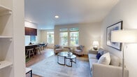Located in Salem, Oregon, this single-floor, 3-bedroom, 2-bathroom unit offers a well-designed layout that makes efficient use of its space. The open-concept living, dining, and kitchen area serves as the heart of the home, with warm hardwood-style flooring flowing throughout. The living room features vaulted ceilings and a corner fireplace, creating a welcoming focal point, while large windows invite generous natural light. The galley-style kitchen is outfitted with rich walnut-toned cabinetry, stainless steel appliances, white countertops, and a convenient breakfast bar with seating. Adjacent to the kitchen, the dining area accommodates a full dining set and benefits from a large window overlooking the surrounding neighborhood. The three bedrooms are comfortably sized, with the primary bedroom featuring a walk-in closet and plush carpeting. Both bathrooms offer wood-toned vanity cabinetry, white countertops, and tub-shower combinations with hardwood-style flooring. A hallway connects the private sleeping quarters to the main living spaces. The overall aesthetic is clean, modern, and neutral, with consistent warm-toned finishes throughout that create a cohesive and inviting atmosphere.