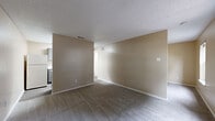 This one-bedroom, one-bathroom unit offers a thoughtfully arranged single-floor layout that maximizes its compact footprint. The living area is open and functional, featuring neutral beige walls, soft carpeted flooring, a textured ceiling, and two windows that invite natural light and views of the surrounding greenery. The space provides a clean, versatile canvas well-suited for a variety of furniture arrangements.

The kitchen is designed in a galley style, running along two parallel walls to make efficient use of space. It features gray cabinetry with marble-patterned countertops, wood-look vinyl flooring, a stainless steel sink, an electric range with overhead ventilation, and a full-size refrigerator. Upper and lower cabinets provide ample storage for everyday needs.

The bedroom is a cozy, carpeted room finished in warm neutral tones, offering a quiet retreat with access to a closet for storage. White trim and doors throughout the unit provide clean contrast against the warm wall colors.

A dedicated bathroom and an additional unclassified room round out the layout, contributing to the overall utility of the space. The consistent use of neutral tones, textured ceilings, and carpeted living areas gives the unit a cohesive, understated character throughout.