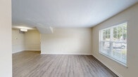 Located at 1101 Ferry Plantation Rd in Virginia Beach, Virginia, this single-floor, 2-bedroom, 2-bathroom home offers a well-organized layout encompassing two living areas, a kitchen, a utility room, a hallway, and a dedicated entrance. The living areas feature warm hardwood-style flooring and neutral-toned walls, creating a bright and open atmosphere. Natural light flows throughout via multiple windows fitted with blinds. The kitchen is outfitted with white shaker-style cabinetry, stainless steel appliances including a refrigerator, range, and dishwasher, complemented by hardwood-style flooring and ample counter space. Both bedrooms are carpeted for comfort, each featuring built-in closets with louvered bifold doors and windows that provide natural light and outdoor views. The spacious primary bedroom offers generous room to furnish comfortably. The two bathrooms are finished with classic white square tile work, accented by a decorative mosaic tile floor in a diamond pattern, and include bathtub-shower combinations equipped with grab bars and curved curtain rods. A utility room provides additional functional space. The exterior features a brick facade, adding traditional character to this well-maintained Virginia Beach home.