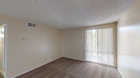 Located at 145-149 Canyon in Oceanside, Unit #276 is a single-floor residence designed with a practical and comfortable layout. The living area features warm, neutral-toned walls, plush carpeting, and a large sliding glass door dressed with vertical blinds that invite natural light and offer a view of the surrounding greenery. The transition between the living space and the entryway is marked by wood-look hard surface flooring, adding a contrast in texture and visual interest. A hallway connects the main living area to the private spaces of the unit, including a bedroom fitted with plush carpet and a generously sized closet. The bathroom is well-appointed with a single-sink vanity featuring a speckled countertop, a combined tub and shower, and wood-look flooring that ties in with the rest of the unit's design. Throughout the space, textured ceilings, neutral wall tones, and consistent trim details create a cohesive and inviting atmosphere. Central air vents are present throughout, ensuring year-round comfort. The functional floor plan makes efficient use of the available space, offering a clean and move-in ready environment in a desirable Oceanside location.