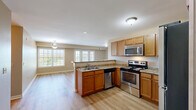 Located at 3535 Piney Creek Dr in Elkhorn, Nebraska, this well-appointed two-bedroom, two-bathroom single-floor home offers a thoughtfully designed layout with a comfortable, functional flow throughout. The open-concept living area seamlessly combines the kitchen, dining room, and living room into one bright, connected space. The kitchen is equipped with stainless steel appliances — including a range, microwave, dishwasher, and refrigerator — complemented by warm wood cabinetry, granite-look countertops, and light hardwood-style flooring that extends throughout the main living areas. A peninsula with a sink opens the kitchen toward the dining and living spaces, which are bathed in natural light from multiple large windows. The dining area features a pendant light fixture and an outdoor view. The spacious primary bedroom includes plush carpeting, a natural light-filled window, and access to a generously sized walk-in closet with wire shelving. The primary bathroom offers a wide vanity, light wood flooring, and accessibility grab bars. The second bedroom is equally well-sized with soft carpeting and its own closet access. The second bathroom includes a full tub-shower combo and a wood-cabinet vanity. Additional highlights include a dedicated laundry area, a balcony, and a hallway connecting all spaces cohesively.