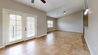 This single-story home on Stonewater Place in Jackson, Tennessee, offers a thoughtfully designed layout across a generously sized floor plan. The open-concept living and dining area serves as the heart of the home, featuring warm tile flooring, vaulted ceilings, a ceiling fan, and a classic white-mantled fireplace. Multiple windows and French doors flood the space with natural light while providing outdoor access. Pendant lighting above the kitchen bar counter connects the living area to the kitchen, which is equipped with warm wood cabinetry, granite-style countertops, black appliances including a refrigerator, electric range, and microwave, and matching tile flooring.

The hallway, also finished in tile, connects the main living areas to the two bedrooms and three bathrooms. The spacious primary bedroom features plush carpeting, a ceiling fan, and a private entrance to an en-suite bathroom. The second bedroom is similarly appointed with carpet and a ceiling fan. A dedicated laundry room includes wire shelving and washer/dryer hookups. Neutral gray tones and white trim throughout lend the home a clean, cohesive aesthetic.