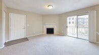 Located within the Arbors Harbor Town community in Memphis, Tennessee, this single-floor residence offers a well-designed layout with a neutral color palette and a blend of hard and soft flooring surfaces throughout. The living room serves as the centerpiece of the home, featuring plush carpeting, a tile-surround fireplace with a white mantel, and a sliding glass door opening onto a private balcony with outdoor views. An open pass-through connects the living area to the kitchen, which is outfitted with white shaker cabinetry, granite countertops, white subway tile backsplash, light wood-look flooring, and a full suite of stainless steel appliances. A dedicated dining area adjacent to the kitchen benefits from multiple windows that invite ample natural light. The bedrooms are generously sized, carpeted, and feature windows overlooking greenery. The primary bedroom includes access to a walk-in closet and an en-suite bathroom with granite countertops, white cabinetry, and a tub-shower combination. A textured ceiling treatment is consistent throughout, and clean white trim and baseboards provide a crisp, finished look across all rooms.