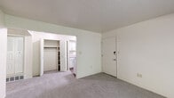 This two-bedroom, one-bathroom unit at 2102 Point West Dr. in Fort Wayne, Indiana offers a practical and efficient single-floor layout. The living area is carpeted and bathed in natural light through a sliding glass door fitted with vertical blinds, which opens to an outdoor view of greenery. A wall-mounted AC unit provides climate control in the main living space.

The kitchen is designed as a galley-style space featuring white cabinetry with modern hardware, light stone-pattern countertops, a double-basin stainless steel sink, and wood-look flooring. White appliances, including a refrigerator and range, complete the functional setup.

The primary bedroom is generously sized and includes a built-in closet with bi-fold louvered doors offering ample storage. The second bedroom is carpeted and features a window with blinds that allows natural light to filter in. Both rooms share access to a full bathroom equipped with a tub-shower combination featuring white tile surround and wood-look flooring.

Throughout the unit, neutral tones, textured ceilings, and carpeted floors create a clean and understated ambiance. The layout connects rooms efficiently, making practical use of the available floor space.