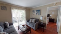 This single-floor, 1-bedroom, 1-bathroom residence offers a thoughtfully arranged layout that maximizes its cozy footprint. Crown molding throughout adds a refined architectural detail, tying each room together with a clean, polished look.

The living area features rich hardwood flooring and is anchored by a sliding glass door fitted with vertical blinds, opening to a private balcony with outdoor views of surrounding greenery. The open sightline from the living area flows seamlessly into the dining space, which is accented with tile flooring and a ceiling fan overhead.

The galley-style kitchen is efficiently designed with ample upper and lower cabinetry in a dark wood finish, granite-style countertops, a double basin sink, tile backsplash, and white appliances including a refrigerator and electric range, all set on easy-care tile flooring.

The bedroom is a comfortable retreat with hardwood floors, crown molding, a ceiling fan, and a window that allows natural light to filter in. The bathroom features a tub and shower combination with full tile surround, offering a clean and functional design.

Overall, this unit presents a warm, livable ambiance with consistent finishes throughout.