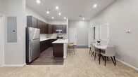 Located at 2301 N Frazier St in Conroe, Texas, this well-appointed single-floor unit offers a thoughtfully designed layout with modern finishes throughout. The kitchen serves as a central highlight, featuring rich dark espresso cabinetry, white countertops, a center island with a double stainless steel sink, and a full suite of stainless steel appliances. Dark hardwood-style flooring anchors the kitchen and dining area, where a marble-top dining table provides an elegant touch. The adjacent living room offers a comfortable, light-filled retreat with tall ceilings, carpet flooring, and a set of French doors that invite natural light and provide outdoor access. The primary bedroom is carpeted and includes a ceiling fan, while the en-suite bathroom features an extended dark vanity with white countertops, hardwood-style flooring, and direct access to a spacious walk-in closet outfitted with multiple shelving tiers and hanging rods. A secondary bedroom with carpet flooring and a large window offers a cozy, well-lit space. Additional features include a dedicated vanity area with dark cabinetry, recessed lighting in the main living areas, and a neutral color palette throughout that creates a clean, cohesive aesthetic across the entire unit.