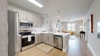 Located in Santa Rosa Beach, Florida, this 2-bedroom, 1-bathroom residence offers a well-designed, single-floor layout with a clean, modern aesthetic. The open-concept kitchen and living area form the heart of the home, featuring light wood-tone cabinetry, white subway tile backsplash, white quartz countertops, and a full suite of stainless steel appliances. A kitchen island with seating provides an ideal casual dining or gathering space, while pendant lighting adds a polished coastal touch. A skylight overhead brightens the kitchen with natural light. The living room is warm and inviting, with light hardwood-style flooring, a ceiling fan, and large windows that allow generous natural light and outdoor views. The primary bedroom offers a comfortable retreat with carpeted flooring, a ceiling fan, and windows with blinds and drape treatments. A dedicated closet features built-in shelving and organizational systems for practical storage. The bathroom is well-appointed with a wood-tone vanity, white quartz countertop, and a tiled tub-shower combination with subway tile surround. The exterior entry features a classic brick facade with a covered entryway. Throughout, the space maintains a cohesive, light, and airy palette well-suited to the Florida coastal setting.