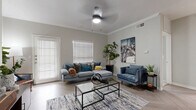 This single-story home offers three bedrooms and two bathrooms within a thoughtfully designed floor plan. The living room serves as the heart of the home, featuring crown molding, light gray walls, a ceiling fan, and light-toned herringbone-patterned flooring. Large windows with horizontal blinds allow natural light to fill the space, creating a bright and welcoming ambiance. A wall-mounted TV and access to adjacent rooms make this an ideal gathering area.

The kitchen is equipped with stainless steel appliances, white cabinetry with matte black hardware, white quartz countertops, and a deep undermount sink. The herringbone flooring continues here, adding visual cohesion throughout the common areas.

Each bedroom features plush carpeting and arched windows that draw in natural light. The primary bedroom is a comfortable retreat with vaulted-style ceilings, pendant lighting, and ample room. The secondary bedrooms are similarly sized and well-lit.

Both bathrooms are finished with gray cabinetry, white quartz vanity tops, and wood-look tile flooring. One bathroom includes a tiled shower-tub combination. Additional storage is provided by two closets. The overall aesthetic is modern and cohesive, with neutral tones and clean finishes throughout.