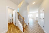 This two-story home combines modern design with functional living across both floors. The main level features warm hardwood-style flooring throughout, an open-concept layout that connects the kitchen, dining, and living areas, and abundant natural light streaming through multiple windows. The kitchen is a standout, outfitted with white shaker cabinets, granite countertops, a subway tile backsplash, stainless steel appliances including a refrigerator with ice and water dispenser, and a peninsula that provides additional prep and seating space. The living area benefits from high ceilings and direct access to the exterior through a rear door. A convenient powder room on the main floor features a pedestal sink and round mirror. A beautifully crafted staircase with a wood newel post and dark metal balusters leads to the upper level. Upstairs, the primary bedroom features vaulted ceilings, plush carpet, a ceiling fan, and a large window. The primary bathroom includes a walk-in glass-enclosed shower with white subway tile. An additional full bathroom on the upper level offers a tub-shower combo and a white vanity with under-cabinet storage. Throughout the home, clean white walls and consistent finishes create a cohesive, move-in-ready atmosphere.