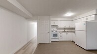 Located in Toronto's Lansdowne neighbourhood, this lower-level 2-bedroom, 2-bathroom unit offers a clean, modern aesthetic with a thoughtfully laid-out single-floor plan. Light wood laminate flooring flows consistently throughout the living spaces, complementing the bright white walls and creating a cohesive, airy feel.

The kitchen is well-appointed with white cabinetry, a subway tile backsplash, ample upper and lower storage, and a full suite of white appliances including a refrigerator and electric range. It transitions seamlessly into the adjacent living area, creating an open and functional shared space.

Both bedrooms are finished with the same light laminate flooring and crisp white walls. The primary bedroom features a double closet with panel doors, while the second bedroom benefits from a low-profile window that brings in natural light. The layout provides a comfortable and private retreat for each room.

The two bathrooms are finished with classic white subway tile, lending a timeless and clean look. One bathroom includes a soaker tub with tiled surround, while the other features a stand-alone tiled shower with mosaic floor tile and chrome fixtures.

A hallway connects all rooms efficiently, and the overall design prioritizes simplicity and functionality, making this a well-maintained and move-in ready space.
