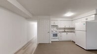 Located in Toronto's Lansdowne neighbourhood, this lower-level 2-bedroom, 2-bathroom unit offers a clean, modern aesthetic with a thoughtfully laid-out single-floor plan. Light wood laminate flooring flows consistently throughout the living spaces, complementing the bright white walls and creating a cohesive, airy feel.

The kitchen is well-appointed with white cabinetry, a subway tile backsplash, ample upper and lower storage, and a full suite of white appliances including a refrigerator and electric range. It transitions seamlessly into the adjacent living area, creating an open and functional shared space.

Both bedrooms are finished with the same light laminate flooring and crisp white walls. The primary bedroom features a double closet with panel doors, while the second bedroom benefits from a low-profile window that brings in natural light. The layout provides a comfortable and private retreat for each room.

The two bathrooms are finished with classic white subway tile, lending a timeless and clean look. One bathroom includes a soaker tub with tiled surround, while the other features a stand-alone tiled shower with mosaic floor tile and chrome fixtures.

A hallway connects all rooms efficiently, and the overall design prioritizes simplicity and functionality, making this a well-maintained and move-in ready space.