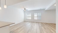 This thoughtfully designed one-bedroom, one-bathroom residence in Kansas City, Missouri offers a clean, modern aesthetic across a single level of well-appointed living space. Light-toned luxury vinyl plank flooring flows throughout the main living areas, complemented by crisp white walls and an abundance of natural light streaming through multiple windows fitted with blinds.

The open-concept living room is spacious and airy, featuring a ceiling fan with light fixture and dual windows that invite natural light and outdoor views. It connects seamlessly to a contemporary kitchen, which serves as a functional centerpiece of the home. The kitchen is equipped with stainless steel appliances, including a French door refrigerator, microwave, and range, all set against classic white subway tile backsplash. White shaker-style cabinetry extends to the ceiling, while a large kitchen island with a quartz countertop and undermount sink provides ample workspace. Elegant pendant lighting anchors the island area.

The generously sized primary bedroom features plush carpet flooring, a ceiling fan, and a window overlooking the outdoors. It connects directly to a dedicated closet and a full bathroom. The bathroom showcases a wide vanity with a taupe countertop, black hardware accents, a walk-in shower with white tile surround, and an in-unit stacked washer and dryer. The overall ambiance is fresh, clean, and move-in ready.