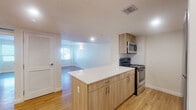 Located at 1770 NE 125th St in North Miami, FL, this single-floor unit offers a clean, contemporary design with a cohesive, open layout connecting the kitchen and living areas. Light wood-tone flooring runs throughout the space, creating a warm and consistent aesthetic.

The kitchen is a standout feature, designed with flat-front light wood cabinetry, white quartz-style countertops, and a peninsula island that provides additional workspace and separates the kitchen from the living area. Stainless steel appliances include a range, built-in microwave, and refrigerator, complemented by a white subway tile backsplash that adds a clean, modern touch.

The living area is generously proportioned, with bright white walls, recessed lighting, and a large window fitted with horizontal blinds that allows natural light to fill the room. Wall-mounted light fixtures provide warm accent lighting throughout.

The bathroom features a framed rectangular mirror, an undermount sink set in a stone-look countertop, and a clean, neutral color palette. Louvered closet doors and visible HVAC vents complete the practical, well-appointed interior. The overall ambiance is light, airy, and move-in ready.