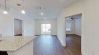 This thoughtfully designed 2-bedroom, 2-bathroom single-story residence offers a clean, contemporary aesthetic throughout. The open-concept kitchen and living area forms the heart of the unit, where dark espresso cabinetry contrasts elegantly with light granite countertops. A peninsula with pendant lighting provides additional workspace and casual seating, while stainless steel appliances—including a refrigerator, range, and microwave—complete the well-appointed kitchen. Hardwood-style flooring runs consistently throughout the unit, adding warmth and visual continuity.

The living area is bright and welcoming, benefiting from recessed lighting and a sliding glass door that introduces natural light and provides outdoor access. Both bedrooms are comfortably proportioned, each equipped with ceiling fans and windows fitted with blinds. The primary bedroom connects directly to an en-suite bathroom featuring a double vanity with granite countertops, dark cabinetry, a large mirror, and a tiled walk-in shower. A dedicated walk-in closet with wire shelving provides practical storage. The second bathroom mirrors the same refined finishes. Crisp white walls and clean trim throughout lend the space a fresh, move-in-ready quality.