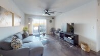This thoughtfully renovated single-floor space blends modern finishes with a clean, minimalist aesthetic. The open living area is anchored by gleaming polished concrete floors and a ceiling fan, creating a bright and airy atmosphere. The space transitions seamlessly into a galley-style kitchen, where white shaker cabinetry, dark granite countertops, a bold dark subway tile backsplash, and stainless steel appliances — including a refrigerator, range, microwave, and dishwasher — come together for a sleek, functional design. Large-format marble-look porcelain tile continues through the kitchen and into the bathroom areas, providing a cohesive flow throughout. The bedroom features the same polished concrete flooring, a ceiling fan, and a window that allows natural light to fill the room, along with access to a walk-in closet. The updated bathroom is a standout, showcasing a walk-in shower with full marble-look tile surround, hexagonal dark tile flooring at the shower base, a dark granite vanity top, and modern black hardware accents. A dedicated vanity corridor with additional storage cabinetry leads to a separate walk-in closet, enhancing functionality. The crisp white walls throughout contribute to the space's clean, contemporary character.