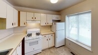 This two-floor home offers a practical and comfortable layout across two levels, designed to maximize functionality. The living area on the main floor features soft neutral carpeting and is bathed in natural light through a large sliding glass door fitted with vertical blinds, complemented by an additional side window. The clean white walls and flush ceiling lighting give the space a bright, open feel.

The kitchen is well-equipped with white cabinetry featuring wood-tone accents, providing ample storage above and below the countertops. A gas range, refrigerator, and dishwasher are all included, alongside a double sink positioned beneath a window that allows natural light into the workspace. The countertops offer a practical surface for meal preparation, and durable tile-style flooring completes the room.

Both bedrooms are located upstairs, each carpeted and featuring multiple windows that invite natural light from multiple directions, creating airy and versatile spaces. The full bathroom on the upper level includes a tub/shower combo, toilet, and vanity with tile flooring, while a half bathroom is also available for added convenience. Overall, the home presents a clean, neutral aesthetic suited for everyday living.