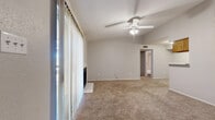 This single-floor residence offers a functional and comfortable layout across two bedrooms, two bathrooms, and a living room, all finished with soft wall-to-wall carpeting throughout the main living areas. The spacious living room serves as the heart of the home, highlighted by a white-surround fireplace, a ceiling fan with integrated lighting, and a large sliding glass door fitted with vertical blinds that fills the room with natural light. The kitchen features warm wood-toned cabinetry, a built-in electric range, and durable hard flooring, with an adjacent open area ideal for dining. Both bedrooms are carpeted and well-lit by windows with blinds, offering quiet and comfortable retreats. The primary bedroom includes access to a dedicated walk-in closet with built-in shelving and hanging rods, providing generous storage. A second closet serves the additional bedroom. The two bathrooms are cleanly appointed, with one featuring classic white subway tile surrounding a full soaking tub and shower combination, set above wood-look hard flooring. Neutral gray tones throughout the walls create a cohesive, understated aesthetic, making the space move-in ready and easy to personalize.