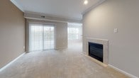Located at 50 Turnberry Ct in Bear, Delaware, this single-floor home offers a well-designed layout filled with thoughtful architectural details. Elegant arched doorways connect the living spaces, creating a seamless flow throughout the home. The expansive living area is anchored by a tile-surround fireplace and features large sliding glass doors and windows that invite abundant natural light and outdoor views. Plush wall-to-wall carpeting runs through the living, dining, and bedroom areas, providing warmth and comfort underfoot. A decorative accent wall adds a touch of character to one of the main living spaces. The kitchen is accessible through a graceful arched entry and is equipped with white cabinetry, dark granite-style countertops, and black stainless steel appliances including a range, microwave, and refrigerator, all set over durable hardwood-style flooring. The bedrooms are generously sized, with one featuring a walk-in closet and ample storage. Bathrooms are finished with tile flooring and full tub-shower combinations with clean white surrounds. Crown molding accents select rooms, adding a refined finishing touch. The overall ambiance is bright, neutral, and move-in ready.