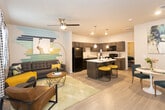 Located at 7117 19th St in Lubbock, TX, this single-story unit offers a thoughtfully designed open-concept layout that seamlessly connects the living area and kitchen. The living room is bright and welcoming, featuring light wood-look flooring, a ceiling fan, and windows dressed with patterned curtains that allow natural light to filter in. A bold wall mural adds a vibrant artistic focal point to the space.

The kitchen is a standout feature, showcasing rich dark-stained cabinetry that extends to the ceiling, offering ample storage. White countertops provide a clean contrast, while a central island with bar seating serves as both a prep space and casual dining area. Pendant lighting above the island adds a modern touch, and black appliances — including a refrigerator, range, microwave, and dishwasher — complete the well-equipped space.

The bedroom is a comfortable retreat with light wood-look flooring, a ceiling fan, and windows that bring in natural light. The bathroom features matching dark cabinetry, a single-sink vanity with a framed mirror, wood-look tile flooring, and a shower with a curtain enclosure. The cohesive design language and modern finishes throughout create a stylish and functional living environment.
