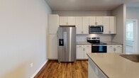 This single-floor residence offers a thoughtfully designed layout that balances comfort and functionality. The open-concept living and kitchen area serves as the heart of the home, featuring rich hardwood-style flooring, recessed lighting, and a ceiling fan. The kitchen is outfitted with stainless steel appliances — including a side-by-side refrigerator with ice maker, electric range, and over-the-range microwave — complemented by crisp white cabinetry, a subway tile backsplash, neutral quartz-style countertops, and a central island with a sink, ideal for both meal prep and casual dining.

The bedrooms are carpeted for warmth and comfort, with multiple windows dressed in horizontal blinds that invite generous natural light and outdoor views. Ceiling fans add to the comfort of each room. A spacious walk-in closet features built-in shelving and hanging rods, providing ample storage.

Two bathrooms serve the residence: one features a glass-enclosed walk-in shower, a single vanity with a framed mirror, and hardwood-style flooring, while the second includes a full soaking tub-shower combo and a matching vanity. A dedicated in-unit laundry area houses a full-size top-loading washer and dryer. Neutral gray walls throughout lend the space a clean, contemporary aesthetic.