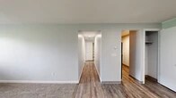 Located at 4389 Plantation Blvd in Liverpool, NY, this single-floor, 2-bedroom, 1-bathroom unit offers a functional and straightforward layout across a compact but well-organized footprint. Neutral light gray walls and white trim are consistent throughout, lending a clean and cohesive look to the space.

The living room features wall-to-wall carpet, providing a comfortable and quiet atmosphere. A central hallway connects the main living area to the rest of the unit and includes two closets, offering practical storage. The hallway and common areas feature wood-style plank flooring that adds warmth and is easy to maintain.

The kitchen is equipped with warm-toned wood cabinetry, laminate countertops, a stainless steel sink, and includes a dishwasher. The primary bedroom is a well-sized room with carpet flooring, a window unit air conditioner, baseboard heating, and an exterior-facing window. The second bedroom also features carpet flooring and a window that allows natural light.

The full bathroom includes a tub/shower combo with a white surround, wood-style flooring, and clean white fixtures. Overall, the unit presents a practical and move-in-ready living environment.