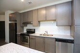This single-floor residence offers a thoughtfully designed layout with a consistent, modern aesthetic throughout. The kitchen serves as a standout feature, equipped with stainless steel appliances including a refrigerator, electric range, and dishwasher. Gray shaker-style cabinetry pairs with a classic white subway tile backsplash and light granite countertops, which extend to a generous kitchen island with pendant lighting overhead. Track lighting and light wood-style flooring complete the kitchen's contemporary look.

The entry area welcomes residents with the same light wood-style flooring, a full-light entry door with transom window, and a large window fitted with blinds that frames views of surrounding greenery, filling the space with natural light.

The bedrooms feature plush, neutral-toned carpeting and are each equipped with ceiling fans for year-round comfort. Large windows dressed with horizontal blinds allow ample daylight to brighten these restful spaces, while clean white walls and white baseboards create a fresh, open feel.

The bathroom is finished with light tile flooring, a dark espresso-toned vanity topped with granite, a framed mirror, and a full tub-shower combination, offering a functional and polished space. Throughout the residence, the design is clean, neutral, and move-in ready.