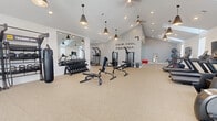 This thoughtfully designed fitness center offers a generous, open floor plan spread across a single level, delivering a comprehensive workout environment for a wide range of fitness needs. The space is anchored by striking vaulted ceilings that amplify the sense of openness, complemented by an array of stylish cone-shaped pendant lights, recessed lighting, and ceiling fans that keep the atmosphere comfortable. Skylights and multiple windows bathe the interior in natural light, creating an energizing ambiance reinforced by a bold wall inscription reading "Calm, Cool, Collected."

The facility is thoughtfully divided into distinct training zones. A dedicated cardio area houses treadmills, ellipticals, and a stair climber, each paired with mounted flat-screen monitors. The strength training section features a full dumbbell rack, cable machines, adjustable benches, and a pull-up/dip station. A designated Training Zone wall organizes TRX suspension trainers, kettlebells, medicine balls, and a heavy punching bag for functional and combat-style workouts. A spin zone with Peloton-style cycling bikes and full-length mirrors rounds out the offerings. The durable speckled flooring throughout ties the space together, providing a clean, professional aesthetic suited to serious training.