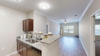 Located at 221 Embassy Dr in Fort Mill, SC, this single-floor residence offers a practical and comfortable layout with two bedrooms, two bathrooms, and two closets. The interior is finished with a neutral color palette throughout, creating a clean and cohesive aesthetic.

The galley-style kitchen is well-equipped with rich dark wood cabinetry, granite countertops, a deep double-basin sink, and black appliances including a refrigerator, range, and dishwasher. Light wood-style flooring runs through the kitchen and main living areas, adding warmth and continuity.

The spacious primary bedroom features plush carpeting and a ceiling fan, offering a comfortable retreat. The second bedroom is similarly appointed with carpet flooring, a ceiling fan, and a window that brings in natural light. Both rooms include dedicated closet space.

The two bathrooms mirror each other in design, each featuring a tub-shower combination, a dark wood vanity with granite countertops, a large mirror with contemporary lighting, and light wood-style flooring. The living area showcases crown molding and large windows that allow abundant natural light.

Overall, the space presents a functional, well-maintained layout with consistent finishes suited for comfortable everyday living in Fort Mill, South Carolina.
