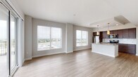 Located along SR-618 W in Tampa, FL, this single-floor residence offers a thoughtfully designed open-concept layout with clean, contemporary finishes throughout. The expansive living area is bathed in natural light through large windows fitted with blinds, offering sweeping views of the Tampa cityscape. Light-toned wood-style flooring flows seamlessly through the main living spaces, enhancing the bright and airy ambiance.

The kitchen is a standout feature, showcasing rich dark-wood cabinetry, granite countertops, a white subway tile backsplash, and a full suite of stainless steel appliances including a refrigerator, range, microwave, and dishwasher. A peninsula island with a built-in sink provides additional prep space and casual seating, while pendant lighting adds a warm, modern touch.

The bedrooms are finished with plush wall-to-wall carpeting and feature large windows that frame city views. Generous closet space with built-in shelving provides ample storage. The bathrooms are well-appointed with dark wood vanities, granite countertops, framed mirrors, and clean tile flooring. One bathroom includes a tub-shower combination with classic white subway tile surround. A hallway connects the living areas to the private spaces, completing this cohesive and functional floor plan.