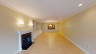 This generously proportioned two-bedroom, two-bathroom single-floor residence offers an expansive and well-appointed layout designed for comfortable living. The open living area is a standout feature, showcasing light hardwood flooring, elegant crown molding, recessed lighting, and a classic fireplace flanked by built-in shelving and cabinetry. A pass-through window connects the living space to the kitchen, enhancing the open feel, while sliding glass doors in the dining area invite natural light and provide outdoor access. The kitchen is well-equipped with warm wood cabinetry, granite countertops, stainless steel appliances including a dishwasher and refrigerator, and tile flooring. Arched doorways throughout the hallway add architectural character and a sense of flow between rooms. The primary bedroom features plush carpeting, a tray ceiling with a ceiling fan, and access to a walk-in closet outfitted with a full built-in organization system including drawers, shelving, and hanging rods. Both bathrooms are finished with granite vanity countertops, tile flooring, and glass-enclosed shower enclosures, with the primary bath offering a spacious dual-sink vanity. Overall, the residence presents a cohesive, neutral palette and a well-structured floor plan ideal for everyday living.