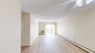Located at 700 Metacom Ave in Warren, Rhode Island, this two-bedroom, one-bathroom residence offers a comfortable and functional single-floor layout. The living room is bright and open, featuring light hardwood-style flooring, a textured ceiling, baseboard heating, and a large sliding glass door dressed with vertical blinds that fills the space with natural light and provides outdoor access. The kitchen is efficiently designed with cream cabinetry, ample counter space, a gas range, and tile flooring, with room for additional appliances. Both bedrooms are carpeted and include ceiling fans with integrated lighting and baseboard heating. The generously sized primary bedroom features dual sliding closets offering substantial storage, while the second bedroom also benefits from natural light and a ceiling fan. A hallway connects the main living areas, with two closets providing additional storage throughout. The full bathroom includes a tub-shower combination. A dedicated laundry area adds everyday convenience. The unit's neutral color palette of warm whites and creams lends a clean, cohesive aesthetic throughout, making it a practical and move-in ready residence.
