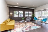 This well-appointed single-floor residence combines contemporary design with functional living across a thoughtfully laid-out floor plan. The open-concept living area makes an immediate impression, featuring an exposed ductwork detail along the ceiling, a bold dark accent wall, and large windows fitted with blinds that invite natural light while framing outdoor views. The space is anchored by warm wood-tone flooring and offers ample room for both relaxing and entertaining. The kitchen flows seamlessly from the living and dining area and is outfitted with stainless steel appliances — including a full-size refrigerator, electric range with overhead microwave, and dishwasher — complemented by white cabinetry, a grey tile backsplash, and stone-finish countertops. A dining nook with a sliding glass door adds additional natural light to the space. The two bedrooms are comfortably sized, each featuring plush carpeting, large windows, and ceiling fans for added comfort. The bathroom is clean and modern, with white cabinetry, a stone-top vanity, a soaking tub, and wood-look flooring. A dedicated closet space adjacent to the bathroom provides generous storage with built-in shelving and hanging rods, rounding out the practical and polished design of this residence.