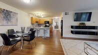 This thoughtfully designed two-bedroom, one-bathroom residence offers a cohesive and functional single-level floor plan. The open-concept living and dining area is anchored by rich hardwood-style flooring and flows seamlessly into the kitchen, creating an inviting space for both relaxing and entertaining. Large sliding glass doors in the living room flood the area with natural light and provide views of the surrounding green outdoor landscape.

The kitchen is a standout feature, equipped with warm honey-toned cabinetry, granite countertops, a stone tile backsplash, and black appliances including a range, microwave, and refrigerator. A breakfast bar with seating adds additional dining flexibility and reinforces the open layout.

Both bedrooms are carpeted and generously sized, each offering windows that bring in natural light. One bedroom features a walk-in closet with built-in shelving, while the other provides ample space for a comfortable sleeping and storage arrangement.

The full bathroom is finished with tile flooring, warm wood cabinetry, and a granite-topped vanity, maintaining the consistent material palette found throughout the residence. Clean lines and neutral tones throughout the home create a bright, welcoming ambiance well-suited to a variety of lifestyles.
