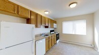 Located at 99 Hemingway Ave in East Haven, Connecticut, this single-floor residence offers a practical and comfortable layout across two bedrooms and one bathroom. The kitchen is well-appointed with warm honey-toned wood cabinetry providing generous storage above and below the counters. A full suite of white appliances includes a refrigerator, dishwasher, electric range, and over-the-range microwave. The countertops feature a neutral stone-look surface, and the kitchen is finished with easy-care tile flooring. A window with horizontal blinds allows natural light to brighten the space. Baseboard heating ensures year-round comfort throughout the unit. The neutral wall tones and flush-mount ceiling lighting contribute to a clean, functional aesthetic. The single-floor layout provides convenient, step-free living throughout the entire residence, making the space accessible and easy to navigate. Overall, the home presents a straightforward and well-maintained living environment suited for those seeking a comfortable, move-in-ready space in East Haven, CT.