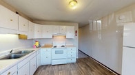 Located at 118 Broadhurst St in Jacksonville, North Carolina, this single-story home offers a straightforward and practical layout designed for comfortable everyday living. The kitchen is equipped with white cabinetry featuring gold hardware, a white electric range with an overhead vent hood, a single-basin sink, and laminate countertops. Wood-look vinyl flooring runs throughout the kitchen, providing durability and ease of maintenance. The living areas are finished with wall-to-wall carpet and feature ceiling fans with integrated lighting, contributing to a comfortable and well-ventilated atmosphere. Textured ceilings are present throughout the home, adding a classic residential character. The bedrooms are carpeted and include windows with blinds that allow for natural light, along with built-in closets with wood panel interiors and double doors for ample storage. The bathroom includes a combined tub and shower unit, a toilet, and matching wood-look flooring that ties in with the rest of the home. Vertical wall paneling accents are found in select areas, adding a subtle design detail. Overall, the home presents a clean, functional living environment well-suited for practical, day-to-day use.