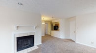 This single-story residence at The Mansion offers a functional and comfortable layout designed for everyday living. The living area serves as the focal point of the space, featuring a classic white-mantled fireplace with tile surround that adds a touch of warmth and character. Neutral-toned carpeting flows throughout the living and bedroom areas, while textured ceilings add subtle dimension overhead.

The kitchen is efficiently arranged in a U-shaped configuration, offering ample cabinetry in warm wood tones, granite-style laminate countertops, and a full suite of black appliances including a refrigerator, electric range, and dishwasher. A pass-through counter connects the kitchen to the adjoining dining or living space, promoting an open feel. Tile flooring and a window with blinds complete the kitchen's practical design.

The bedrooms are carpeted and bright, each featuring windows that allow natural light to filter in. One bedroom includes a ceiling fan with light fixture, while another offers closet access. The bathroom is well-appointed with a granite-style vanity countertop, wood cabinetry, a wide mirror, and a full tub-shower combination. Throughout the space, neutral walls and consistent finishes create a cohesive, move-in-ready environment.