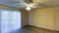 Located at 310 Abbey Ct in Biloxi, Mississippi, this single-story residence offers a straightforward and functional layout designed for comfortable everyday living. The interior features wall-to-wall carpeting throughout the main living area, providing a warm and soft underfoot experience. A ceiling fan with an integrated light fixture is centrally mounted on the textured ceiling, offering both ambient lighting and airflow — a practical feature well-suited to the Gulf Coast climate. The living area is bathed in natural light thanks to a sliding glass door dressed with vertical blinds, which also provides a convenient point of access to the exterior. The walls are finished in a neutral, soft yellow tone that contributes to a bright and welcoming atmosphere. The space reflects a clean, no-frills design with functional details throughout. Its single-floor layout ensures easy accessibility and a seamless flow between areas. Situated in Biloxi, MS, the property benefits from proximity to the Gulf Coast's amenities, beaches, and local community conveniences, making it a practical choice for those seeking a well-located and low-maintenance residence.