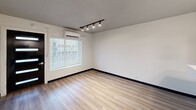 Located at 101 N 11th St in Fort Smith, Arkansas, this one-bedroom, two-bathroom unit offers a thoughtfully designed layout across a single floor. Light wood-style luxury vinyl plank flooring runs throughout, complemented by crisp white walls and bold dark baseboards that create a clean, contemporary aesthetic.

The open-concept kitchen and living area serves as the heart of the unit. The kitchen features two-tone cabinetry — white upper cabinets paired with slate-blue lower cabinets — topped with white countertops and a peninsula that provides additional workspace and a natural division from the living area. Stainless steel appliances, including a refrigerator, range, microwave, and dishwasher, complete the modern kitchen. A stylish pendant light adds warmth above the peninsula.

The spacious primary bedroom comfortably accommodates a variety of furniture arrangements and includes track lighting and a wall-mounted mini-split HVAC unit for individualized climate control. A large window with blinds allows for ample natural light. The unit includes two full bathrooms, one featuring a tub-shower combination with clean white tile surround. Additional storage is provided by a built-in shelving nook. A sleek black entry door with glass panel inserts adds a modern touch to the unit's entrance.