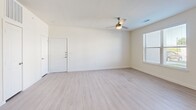 Located in Burleson, TX, this thoughtfully designed one-bedroom, one-bathroom unit offers a clean, modern aesthetic throughout its well-utilized single-floor layout. The open-concept living and kitchen area serves as the heart of the home, featuring light luxury vinyl plank flooring, a large white kitchen island with dramatic pendant lighting, white shaker cabinetry, a grey subway tile backsplash, and a full suite of stainless steel appliances including a range, microwave, dishwasher, and refrigerator. The kitchen's corner window placement invites natural light, enhancing the bright, airy feel of the space. The living room is generously proportioned, with a ceiling fan, multiple windows, and a glass door that opens to an outdoor area, further connecting the interior to the outside. The bedroom is carpeted for comfort, fitted with a ceiling fan, and benefits from natural light through a window. It connects directly to a well-appointed bathroom featuring a soaking tub with tile surround, a single vanity, and direct access to a walk-in closet lined with built-in shelving on multiple walls. A dedicated in-unit laundry area with overhead shelving adds practical convenience. The overall palette of whites and soft neutrals creates a cohesive, welcoming atmosphere throughout.