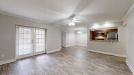 This single-floor residence offers a well-organized layout that balances open communal areas with private bedroom spaces. The living room serves as the heart of the home, showcasing wood-look plank flooring, crown molding, and a ceiling fan with light fixture. A second ceiling fan and a decorative chandelier provide additional lighting, while a glass-paned door with blinds opens to the exterior, allowing natural light to fill the space. Crown molding adds a refined architectural detail throughout the main living area.

The kitchen is thoughtfully designed with a pass-through opening to the living area, wood-toned cabinetry, granite countertops, and stainless steel appliances including a refrigerator, microwave, and gas range. The layout promotes an open, connected feel between cooking and living spaces.

The bedrooms are carpeted in a neutral tone and receive natural light through blinds-covered windows. Each room offers a clean, versatile space suitable for varied furniture arrangements. The bathrooms feature granite-topped vanities with wood cabinetry, tiled tub-shower combinations, and hard flooring, providing a consistent, polished finish throughout. The neutral color palette across all rooms creates a cohesive and move-in-ready aesthetic.