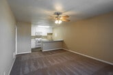 Located at 1939 Wallace Avenue in Costa Mesa, California, this single-floor, one-bedroom, two-bathroom unit offers a well-organized layout designed for comfortable everyday living. The open living area greets you upon entry, featuring warm beige carpeting, neutral-toned walls, and a ceiling fan with a light fixture that provides both airflow and ambient lighting. Natural light filters in through vertical-blind-covered windows, adding brightness to the space.

The kitchen is efficiently designed with white cabinetry, granite-patterned countertops, a double stainless steel sink, and white appliances including a range and microwave. A peninsula countertop creates a seamless connection between the kitchen and the living area, offering additional prep and seating space. The kitchen also features wood-look flooring for easy maintenance.

The bedroom is a generously proportioned room with plush carpeting, a ceiling fan, and two windows dressed with vertical blinds that invite natural light. It includes access to a dedicated walk-in closet equipped with built-in shelving and hanging rods, providing ample storage.

The two bathrooms feature wood-look tile flooring, a tub-shower combination, and vanities with granite-style countertops. The overall aesthetic throughout the unit is clean and neutral, making it highly adaptable to a variety of interior styles.